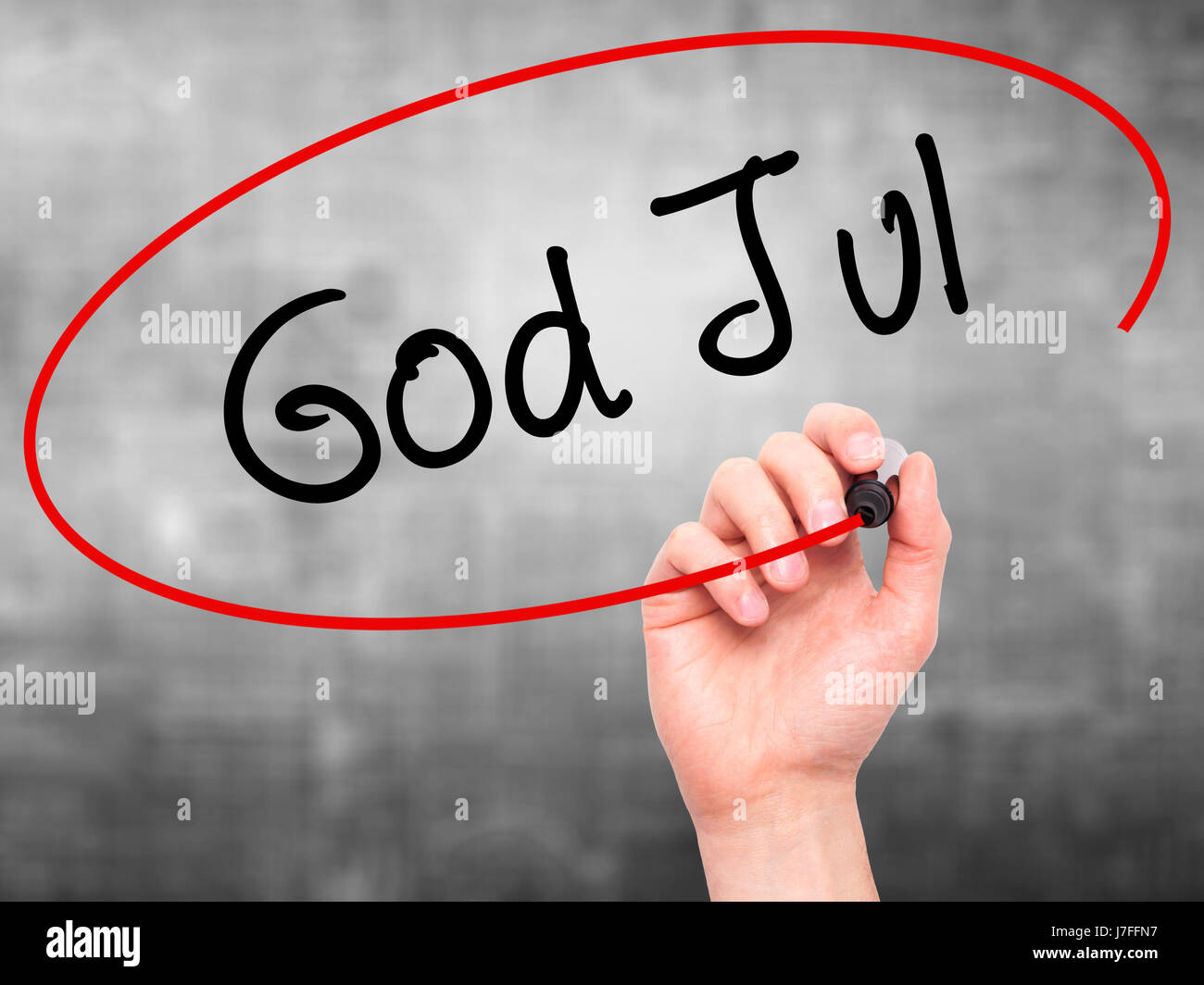Man Hand writing God Jul (Merry Christmas in Swedish) with black marker