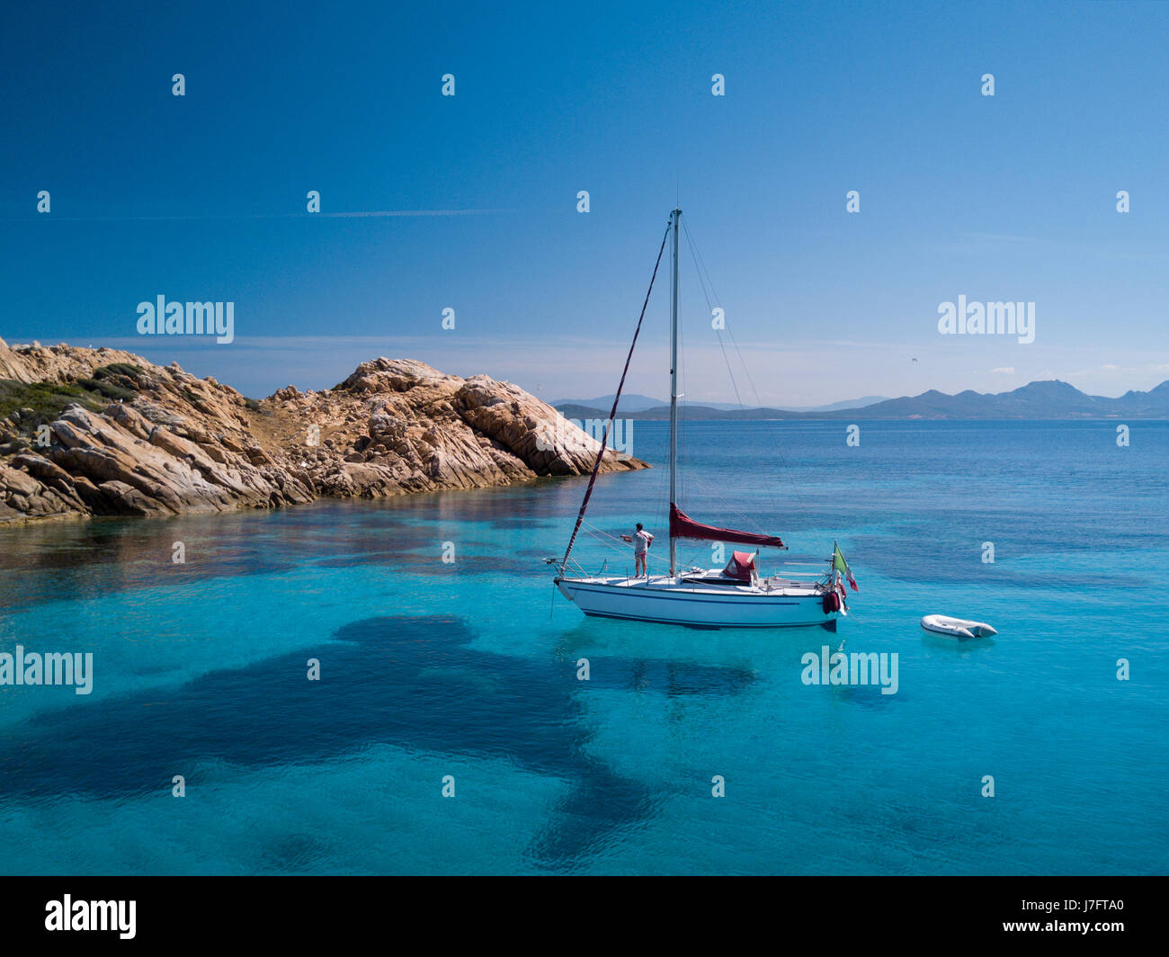 Aerial view of a boat in front of the Mortorio island in Sardinia. Amazing beach with a turquoise and transparent sea. Emerald Coast, Sardinia, Italy. Stock Photo