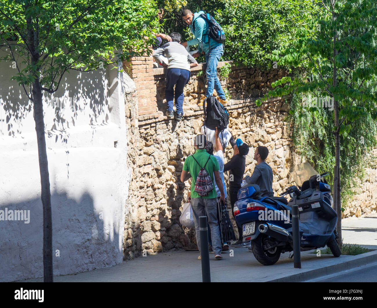 Sellers of fake goods escaping the authorities by scaling a wall. Stock Photo