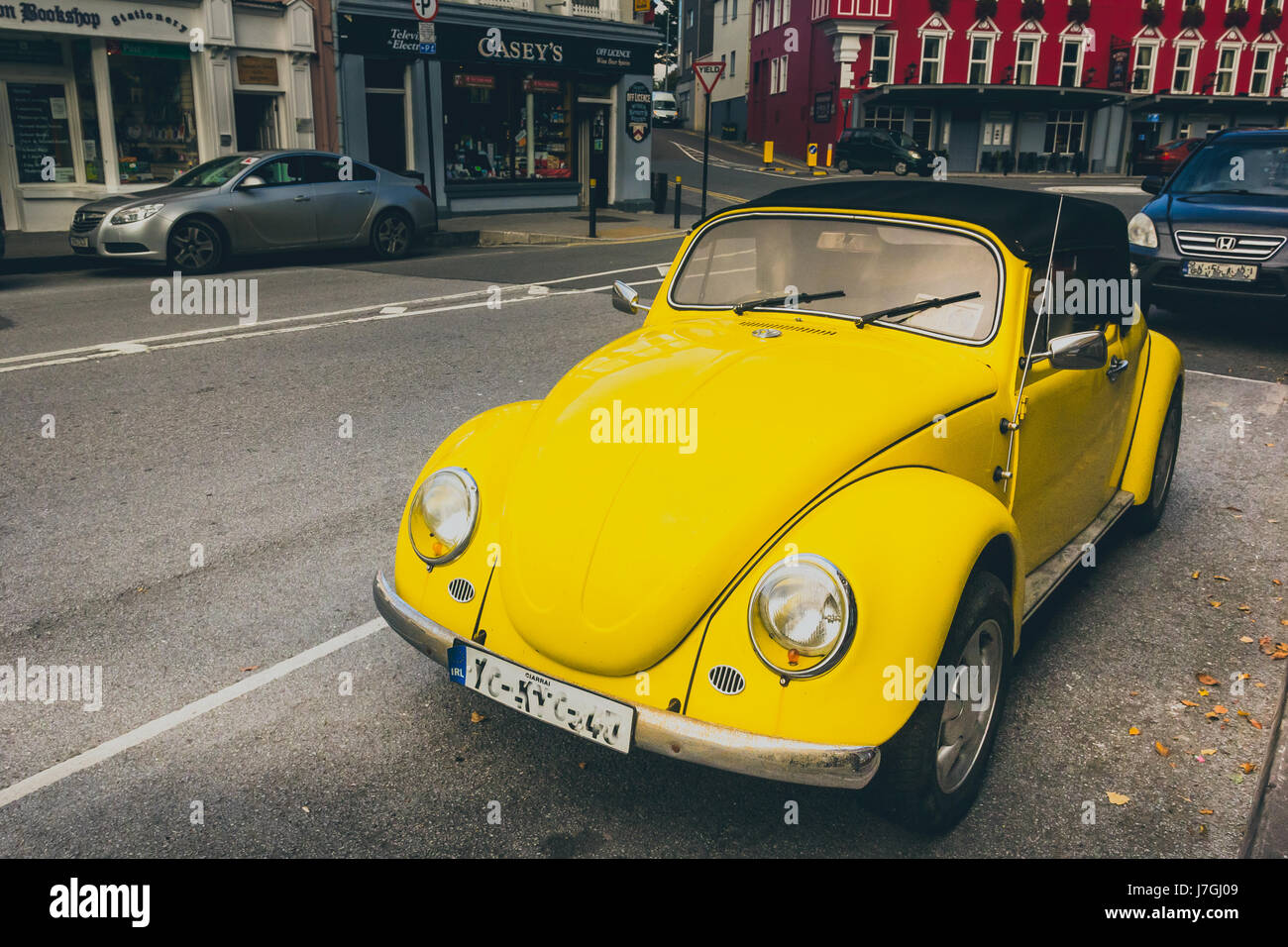 a convertible vintage yellow coloured volkswagen car parked on the road ...