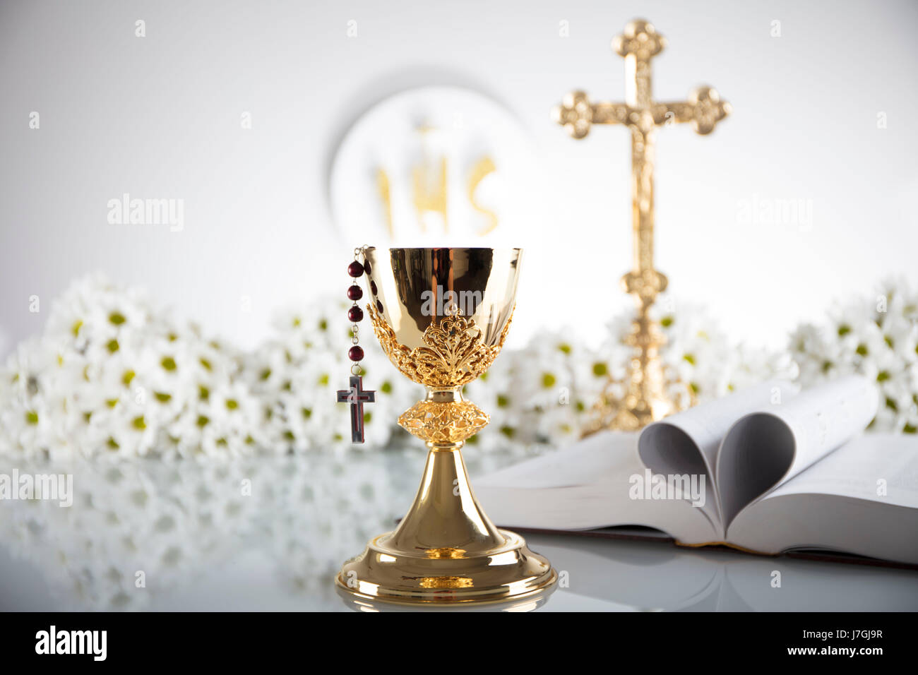 First Holy Communion. Catholic religion theme. Crucifix, Bible, bread isolated on white table and white background. Stock Photo