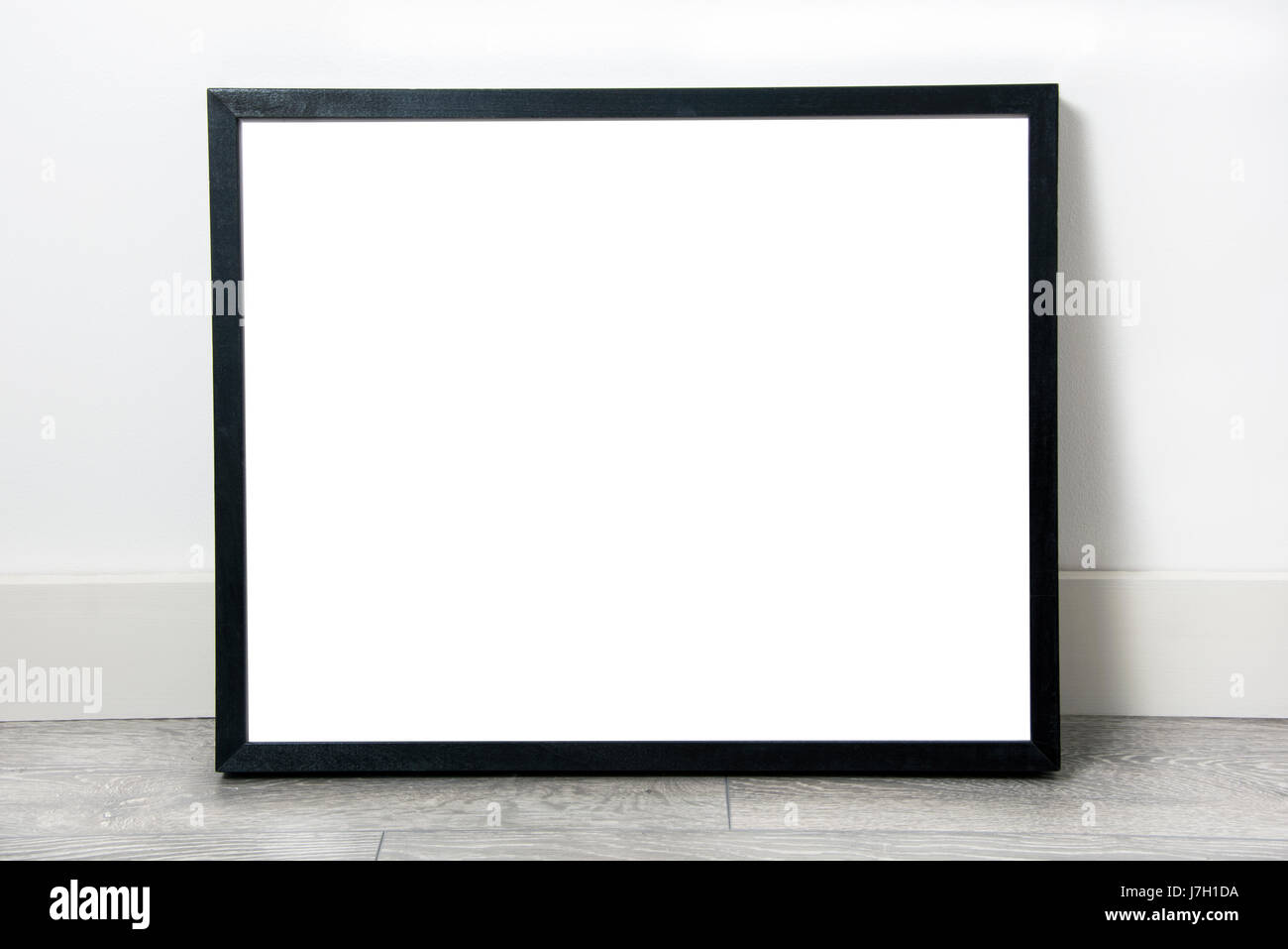 Black rectangular frame, blank inside, leaning against wall on grey oak flooring Stock Photo