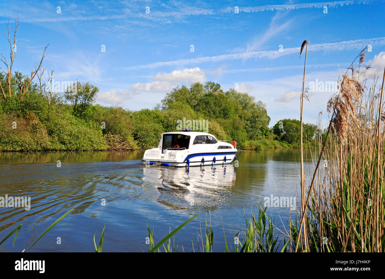 A boat cruising along Fleet Dike in the Norfolk Broads National Park at