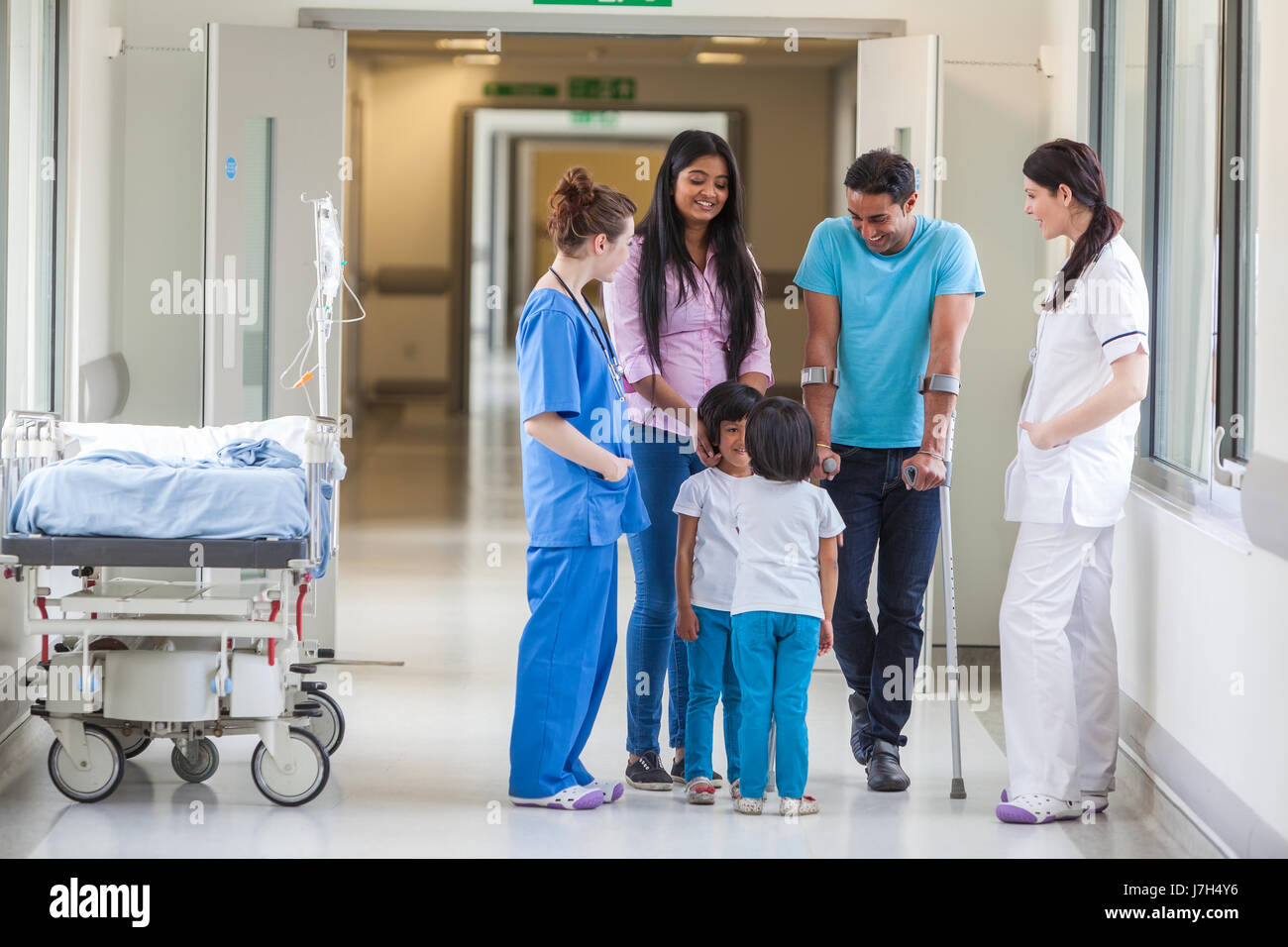 Young Asian Indian family, parents and 2 girl female children with woman doctor and nurse in modern hospital corridor Stock Photo
