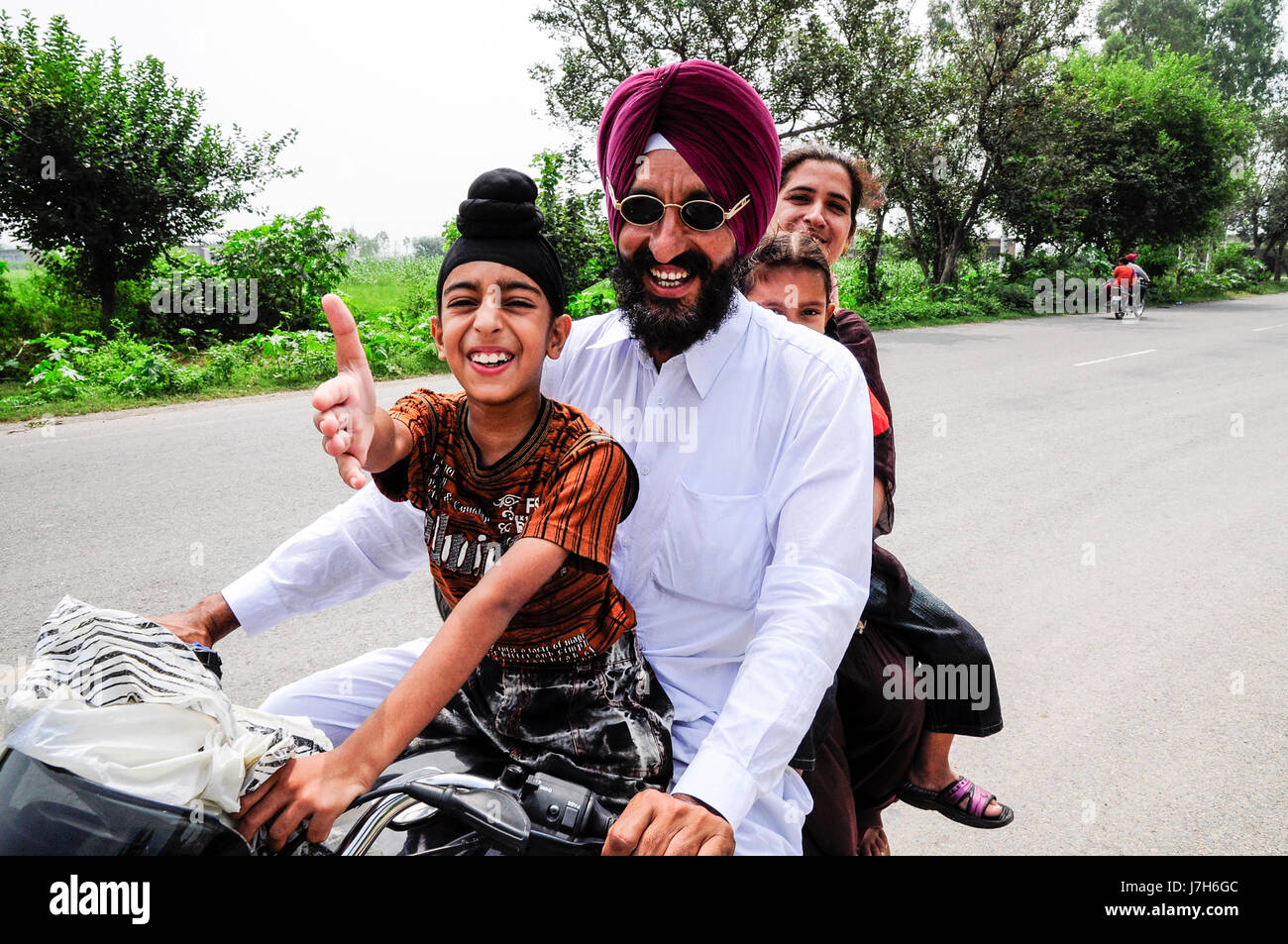 Amritsar, India, september 5, 2010: Sikh Indian family on a motorcycle with son pulling out his hand. Stock Photo