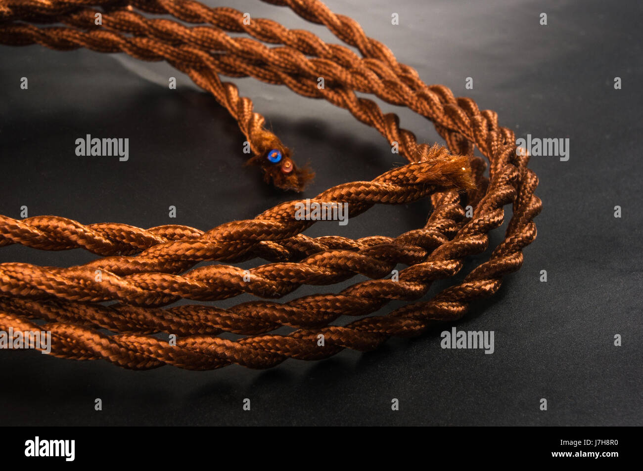 Electric cable in brown braid of fabric in retro style on black ...