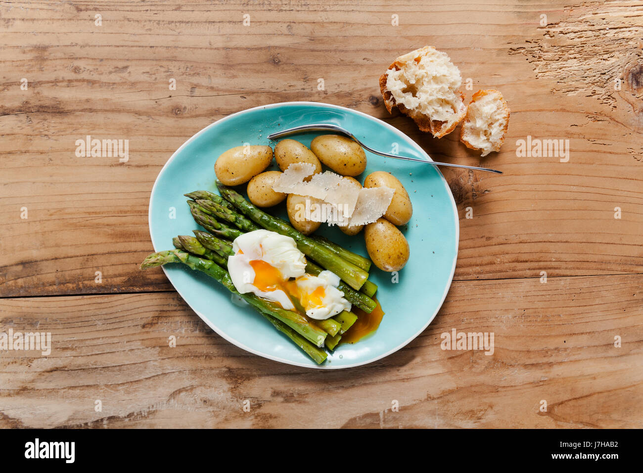 Light spring lunch on the plate. Fried asparagus, fresh potatoes and poached egg with parmesan cheese. healthy food. Stock Photo