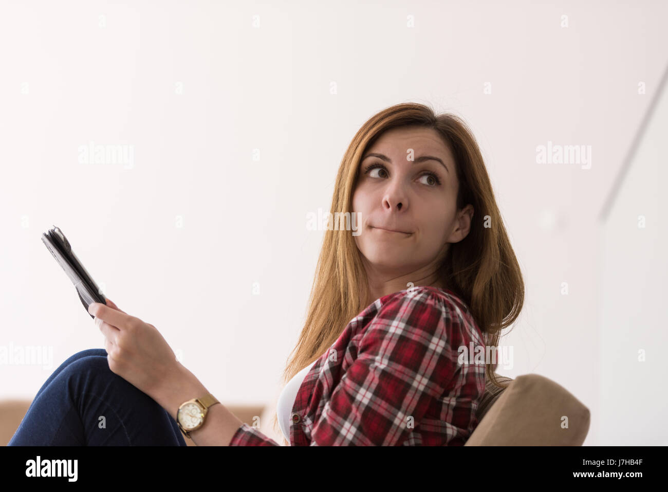 young happy woman sitting on sofa with tablet computer at luxury home ...