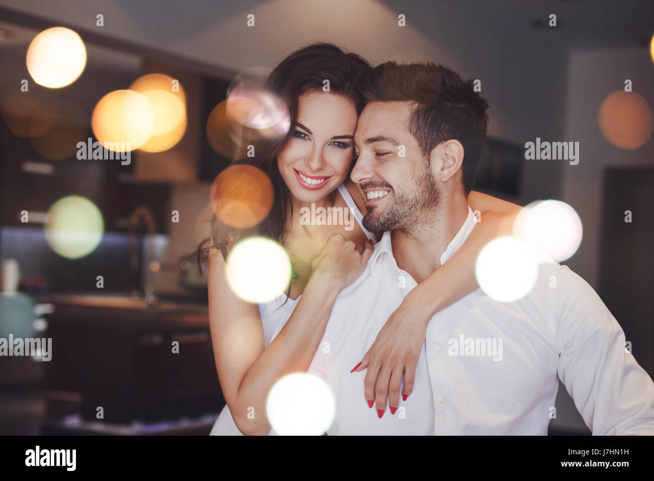 Young successful couple smiling, woman embrace man indoors, bokeh Stock Photo