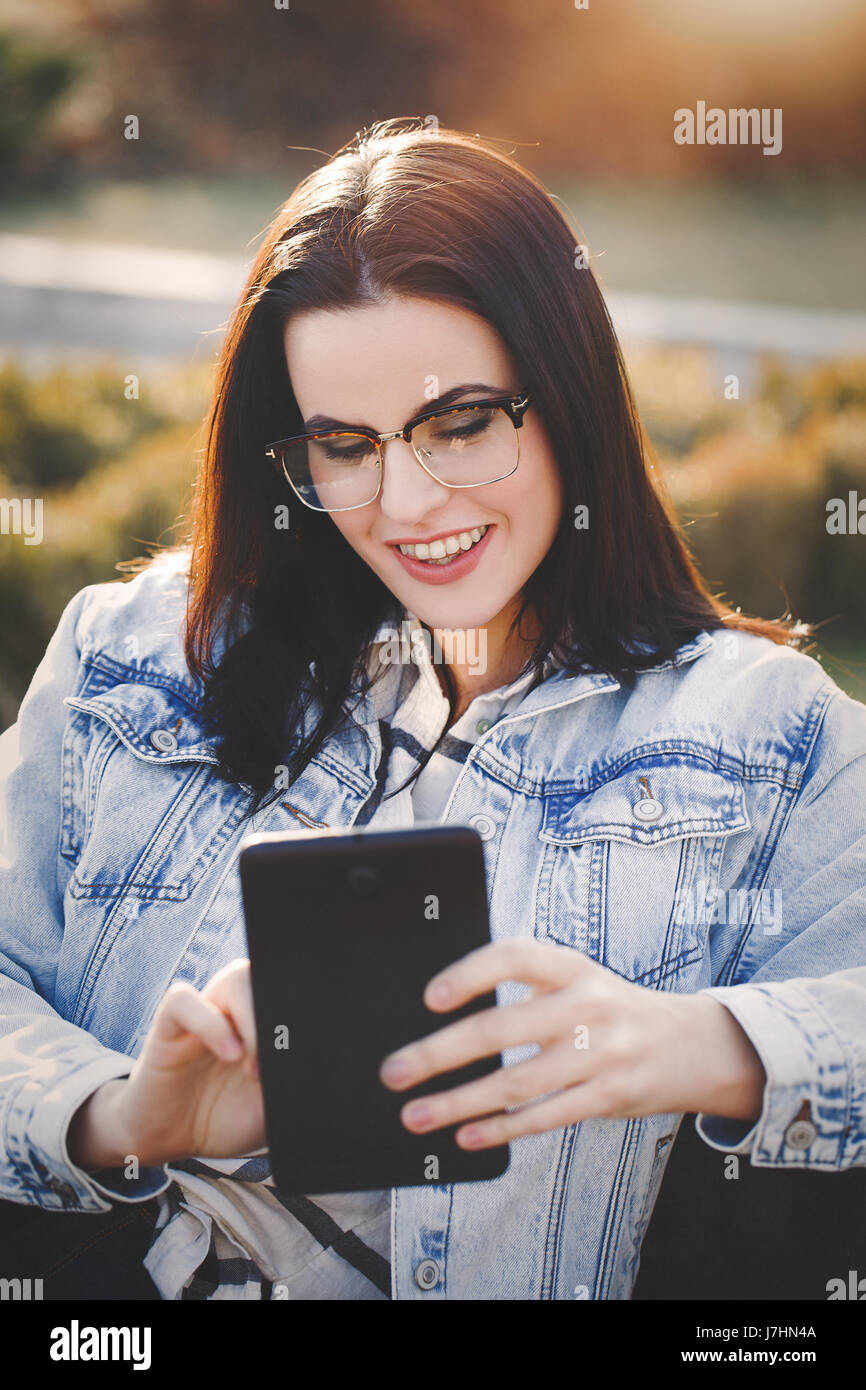 Happy young brunette woman using tablet outdoor Stock Photo