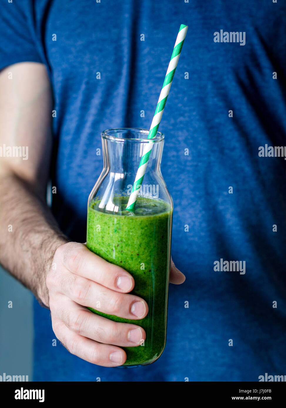 Green smoothie. Man hands holding bottle with freshly made detox green smoothie. Closeup view, selective focus Stock Photo