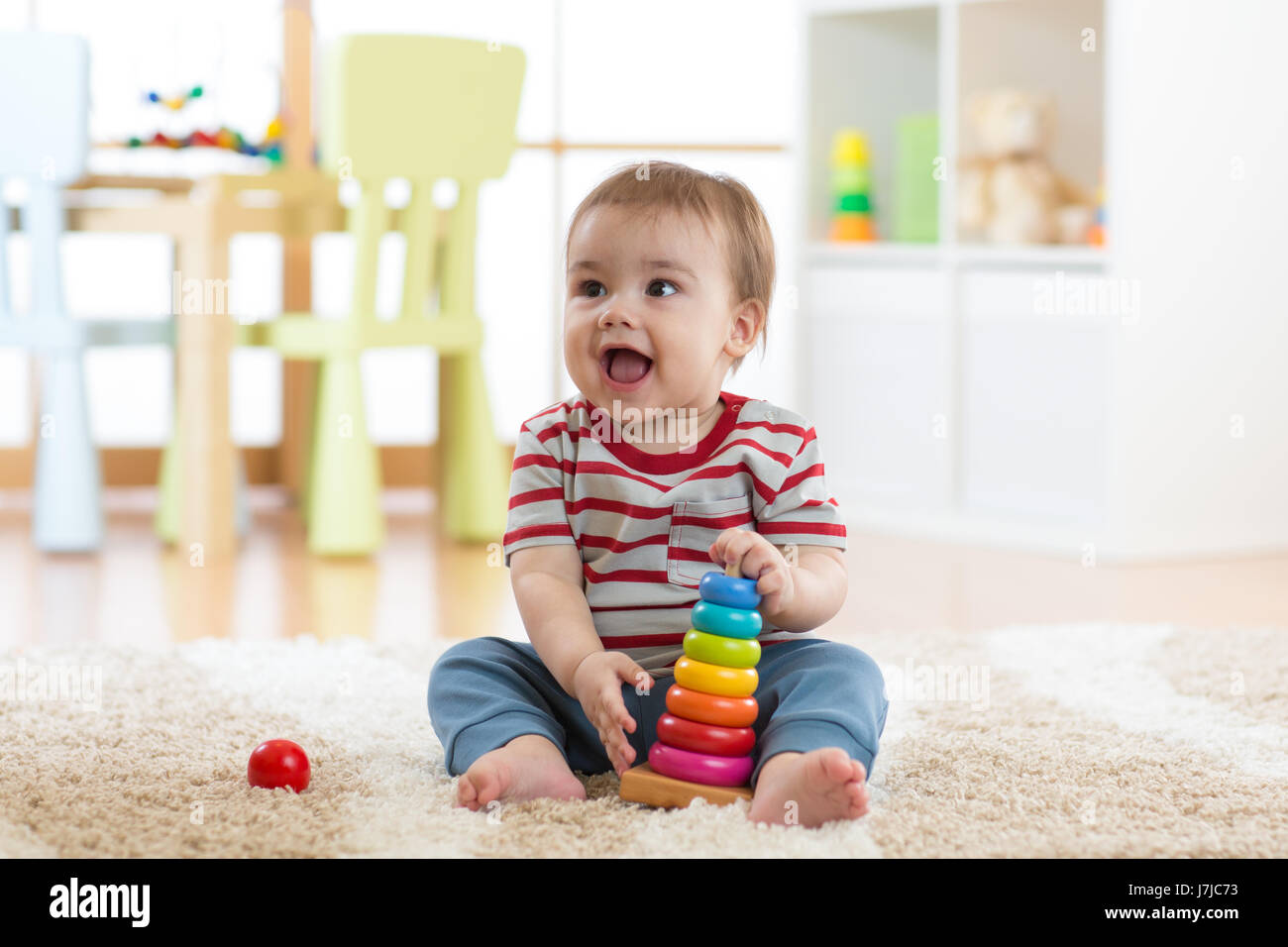 Baby child playing with educational pyramid toys at home. Little kid have fun indoors Stock Photo