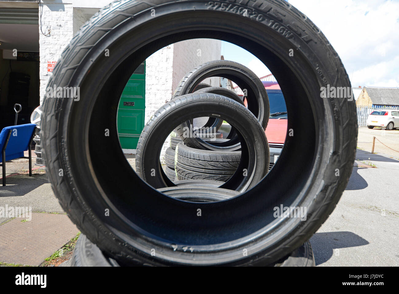 Tyres (tires) outside a back street garage, some stacked standing up
