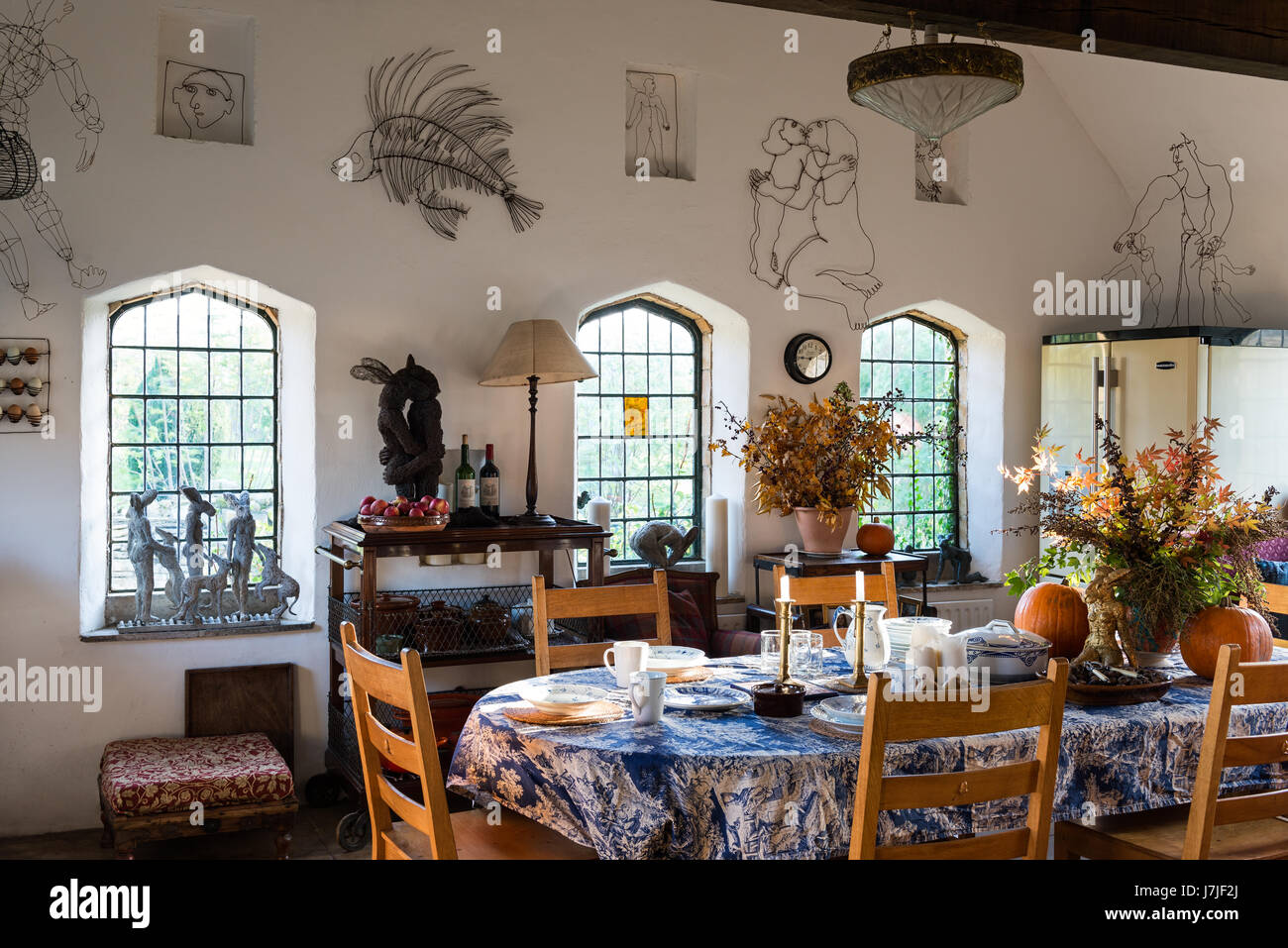 Rustic feeling large kitchen dining room adorned with Sophie Ryder wire sculptures and bunches of autumn leaves. The windows are arched giving the spa Stock Photo