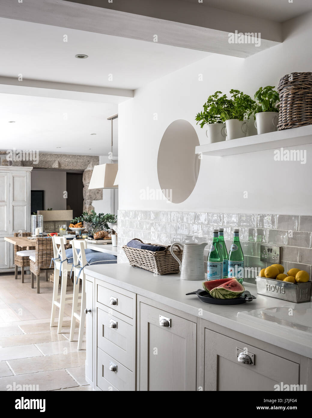 Brick gris Claro wall tiles from Tile Flair in spacious kitchen diner with limestone floor tiles and porthole window Stock Photo