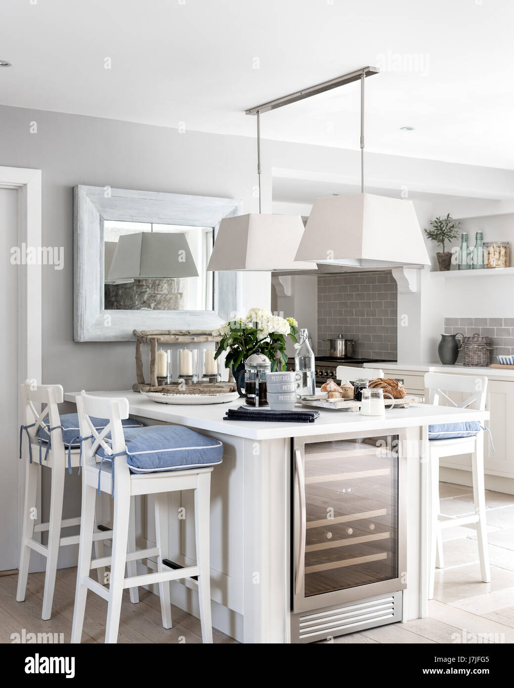 Breakfast bar with white Ingolf bar stools from Ikea and chambray seat pads from The White Company. The pendant lights are by Neptune. Stock Photo