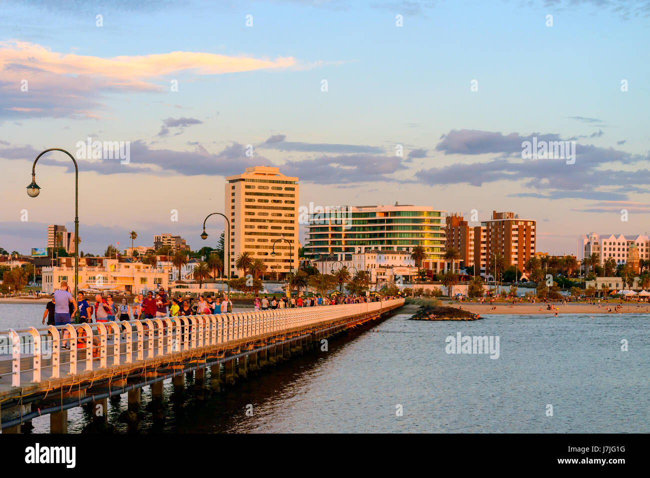 Melbourne, Australia - December 28, 2016: People walking along St. Kilda Beach jetty at sunset on a hot summer day Stock Photo