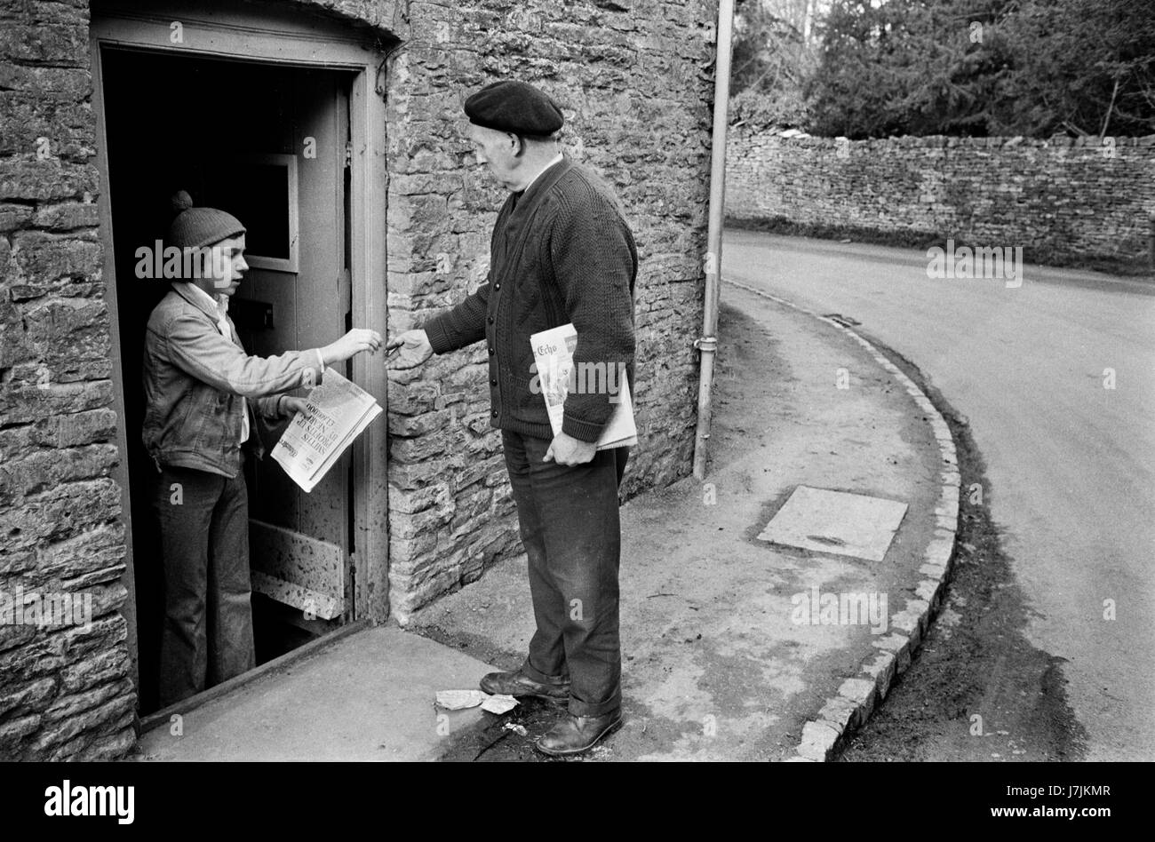 Senior man delivering newspapers in the village Sunday morning delivery. 1970s Britain UK. Village life, keeping busy and fit. The Cotswolds. Lower and Upper Slaughter are twin villages on the River Eye and are know as The Slaughters.  1975 HOMER SYKES Stock Photo