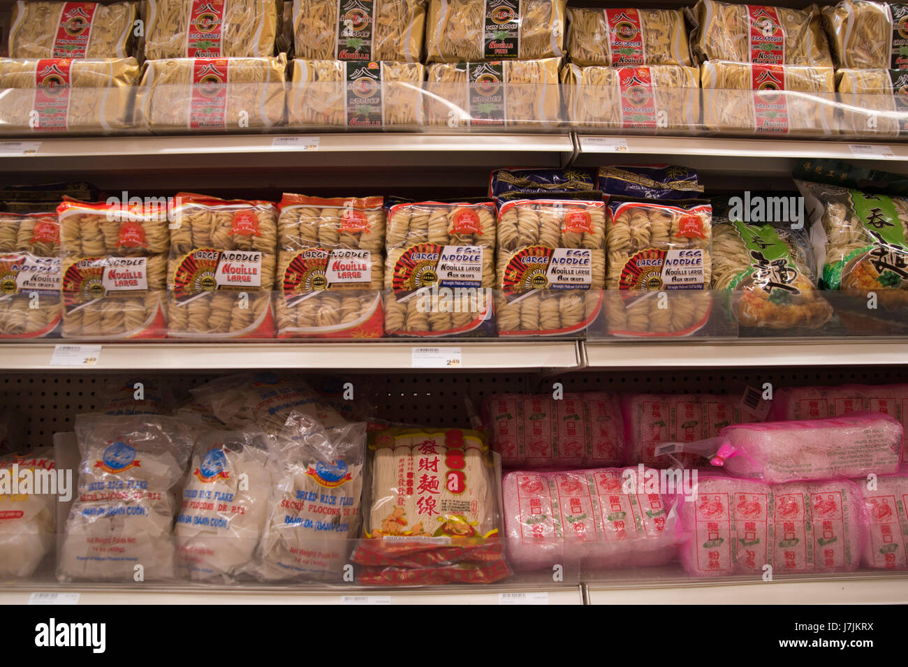 Local asian grocer has aisle of packaged foods, various fruits, meats, and colourful sweet treats. A local store providing foods from other countries. Stock Photo