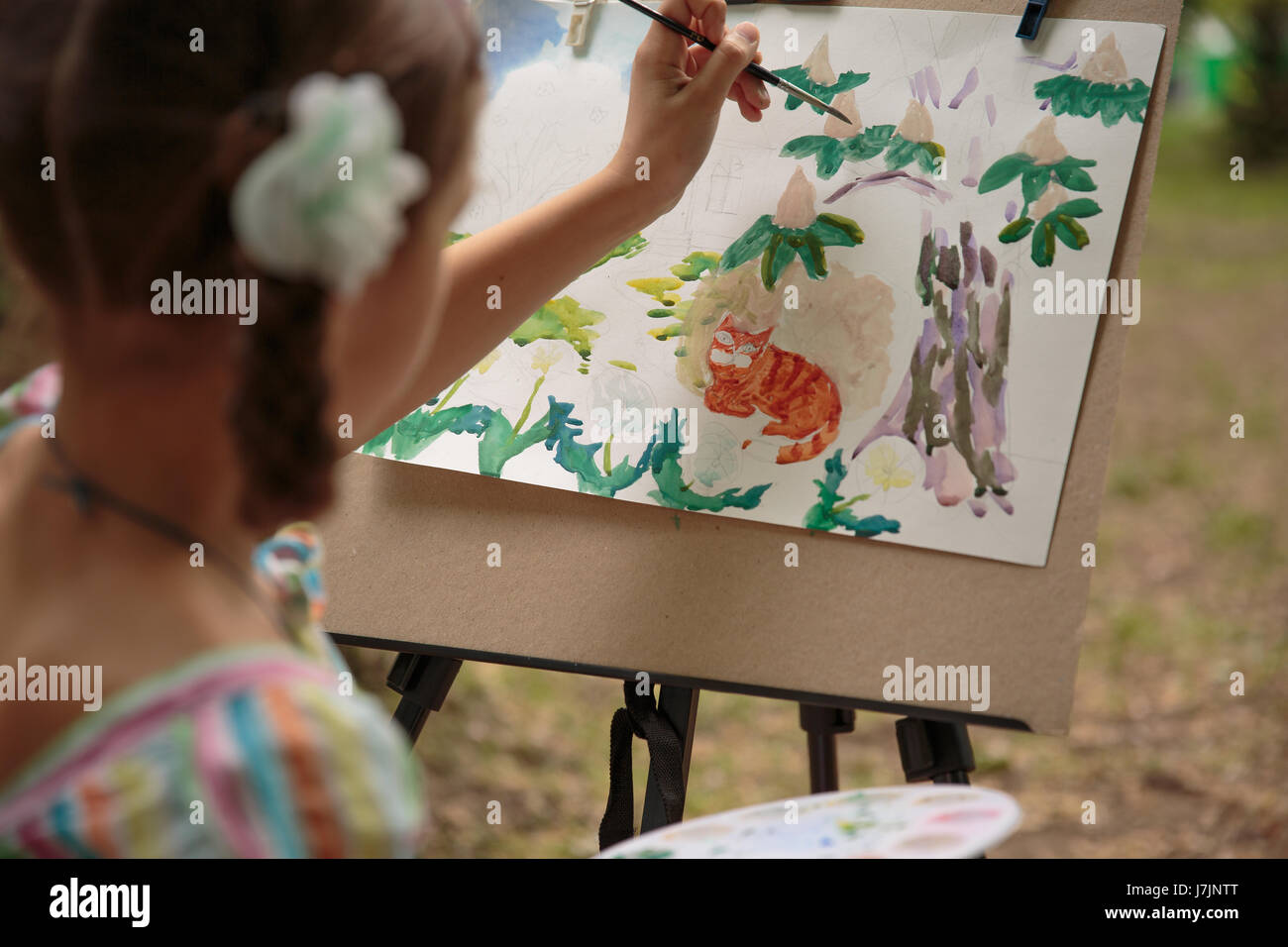 girl paints on an easel in the drawing lesson. Girls Hand draws a ...