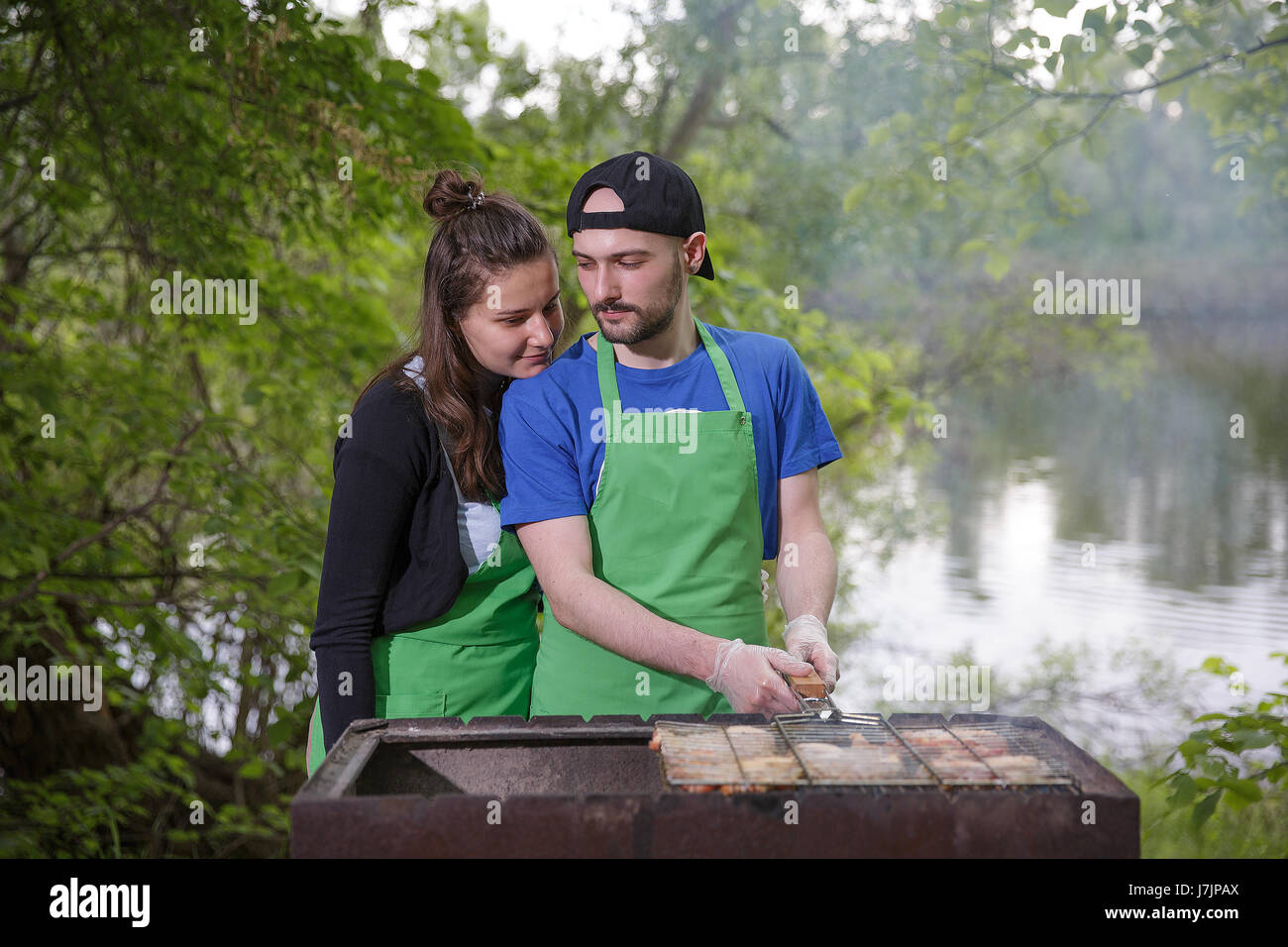 Young couple preparing meat on a grill outdoors Stock Photo