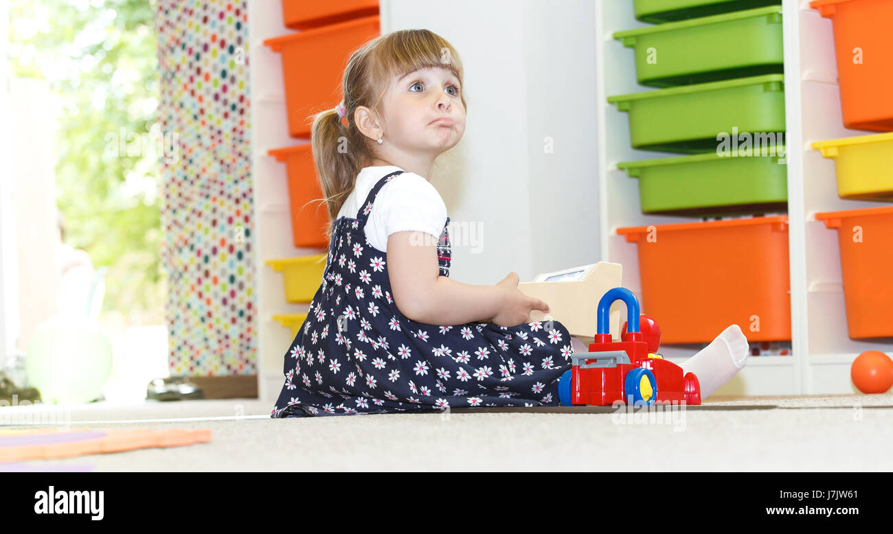 Blonde little girl playing joyfull at the daycare Stock Photo