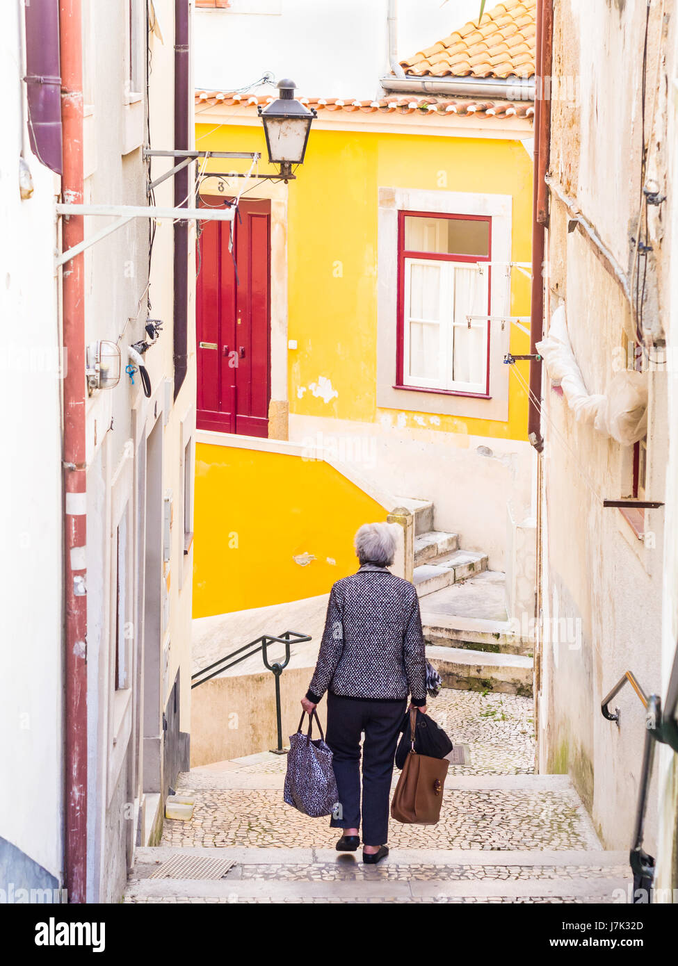 COIMBRA, PORTUGAL - April 04, 2017: Elderly lady walking down the stairs in the old town of Coimbra in Portugal. Stock Photo