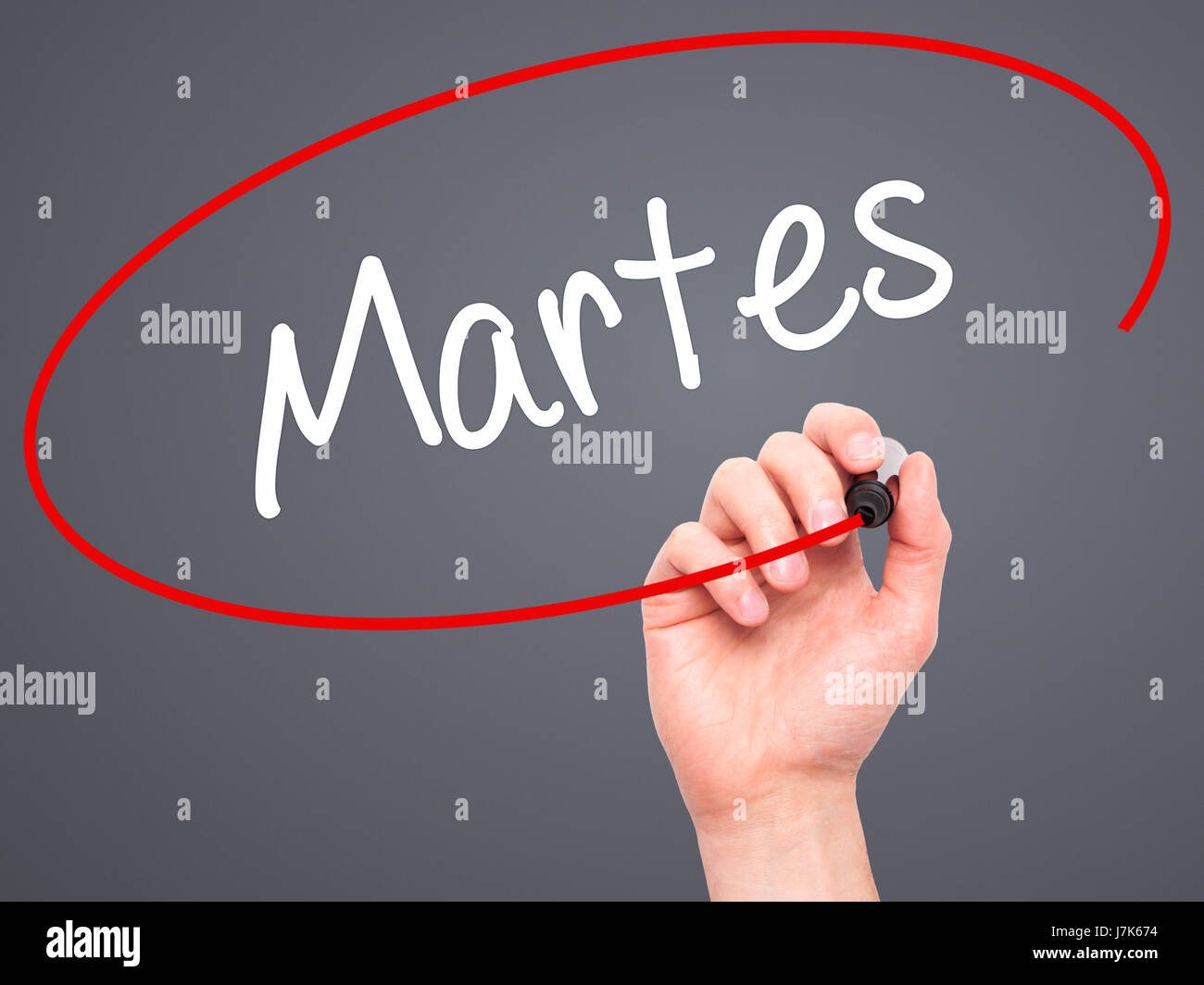 Man Hand writing Martes (Tuesday in Spanish) with black marker on