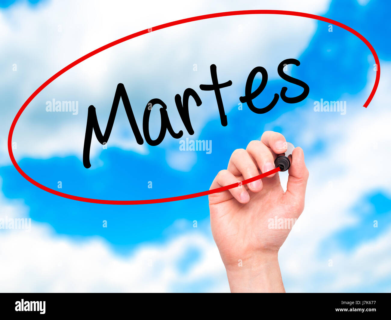 Man Hand writing Martes (Tuesday in Spanish) with black marker on