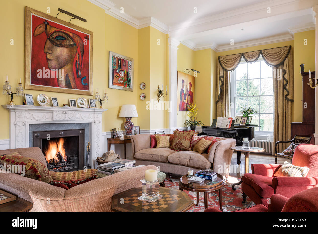 Mixed modern art and antique furniture in large yellow drawing room. The curtain fabric is Agrippina Gold by Marvic Textiles Stock Photo