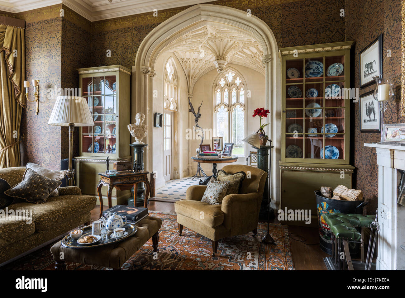 Patterned wallpaper by Zuber in library with antique persian rug and Gothic windows. The sofa and armchairs are from Beaumont & Flectcher Stock Photo