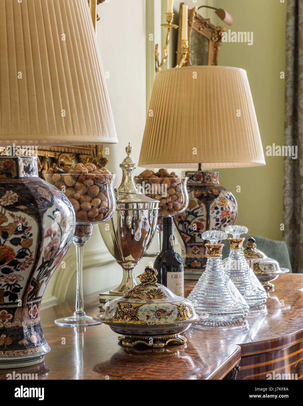 Antique lamp stands on console table with glass decanters Stock Photo