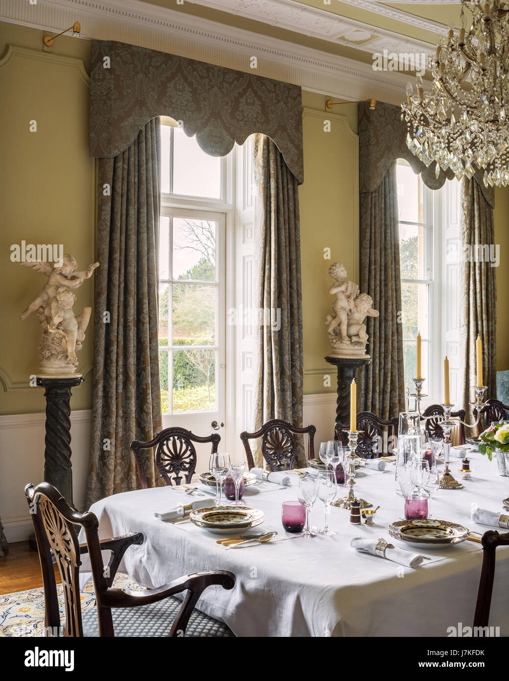 Georgian style dining chairs in grand dining room with glass chandelier marble busts on plinths Stock Photo