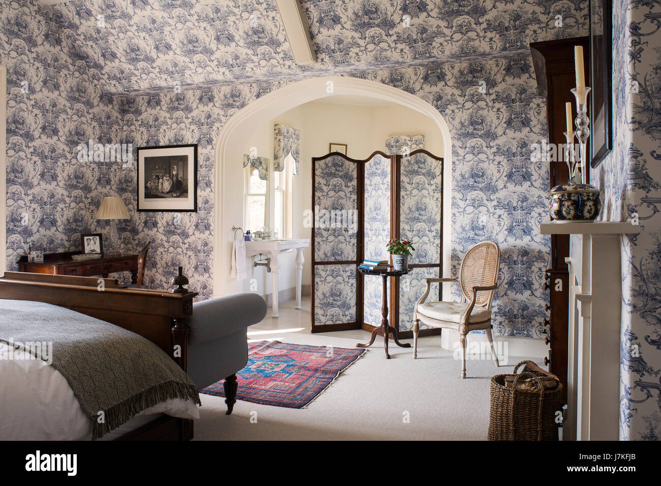 Large ensuite bedroom with toile de jouy wallpaper and matching folding screen. Stock Photo