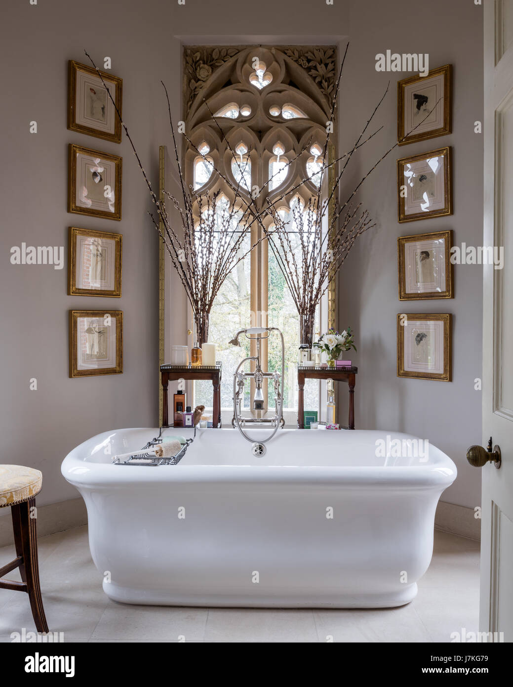 Stand alone bath from Drummonds in bathroom with dramatic gothic window and walls painted in Wax Myrtle by Fired Earth Stock Photo
