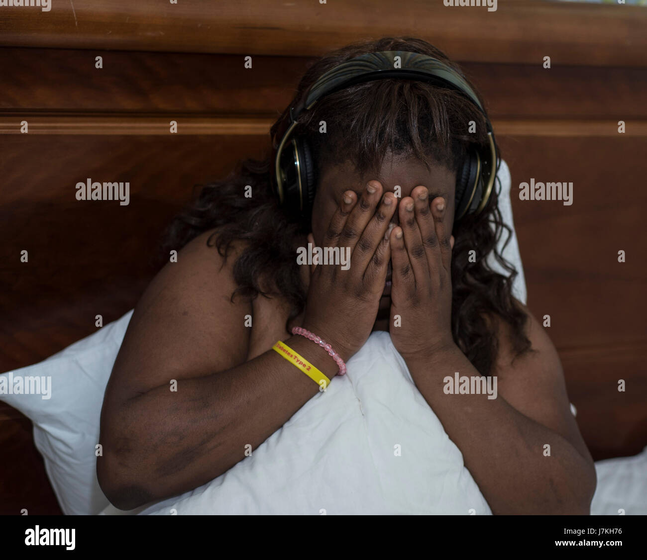 can not sleep, plus sized model with headphones, head in hands Stock Photo