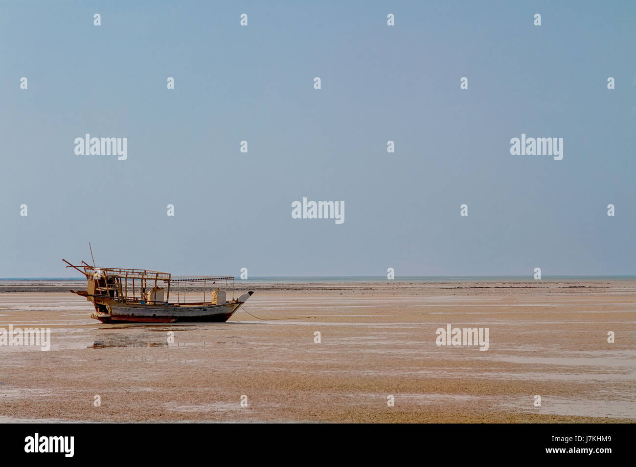 Traditional Dhow boat moored along the coastline during low tide in Al-Ruwais village, Qatar, Middle East. Stock Photo