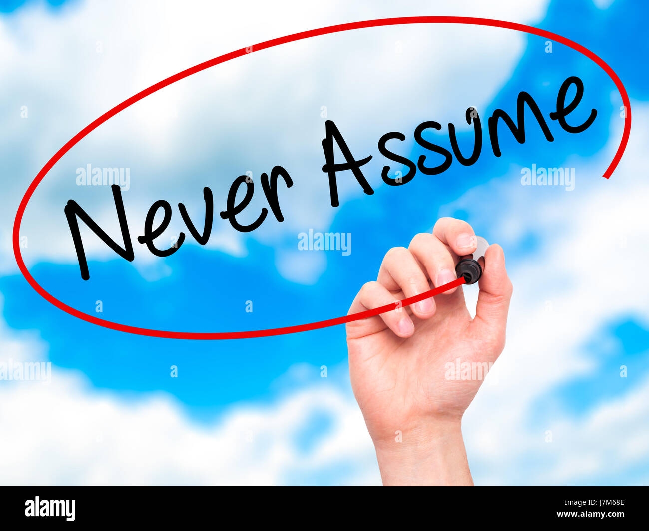 Man Hand writing Never Assume with black marker on visual screen. Isolated on background. Business, technology, internet concept. Stock Photo Stock Photo