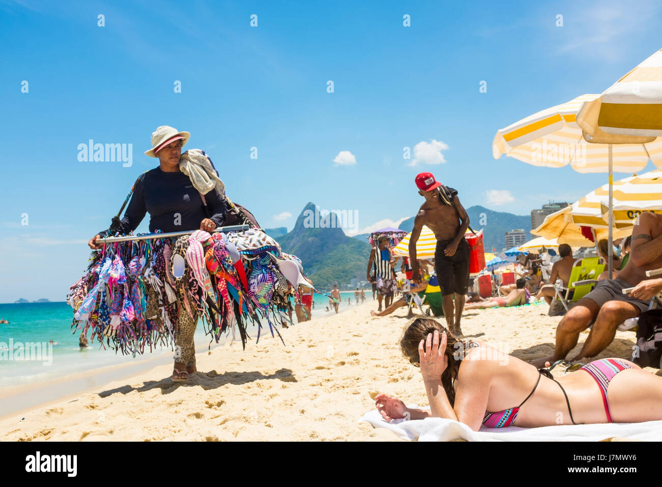 Rio De Janeiro February 5 17 A Beach Vendor Selling Bikinis Passes Beachgoers Enjoying A Hot Summer Day On Ipanema Beach Stock Photo Alamy