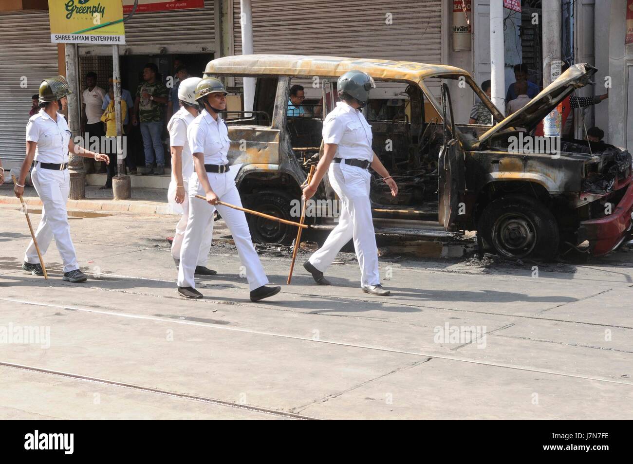 KOLKATA, INDIA - MAY 25: Police personel walk past an torched vehicle ...