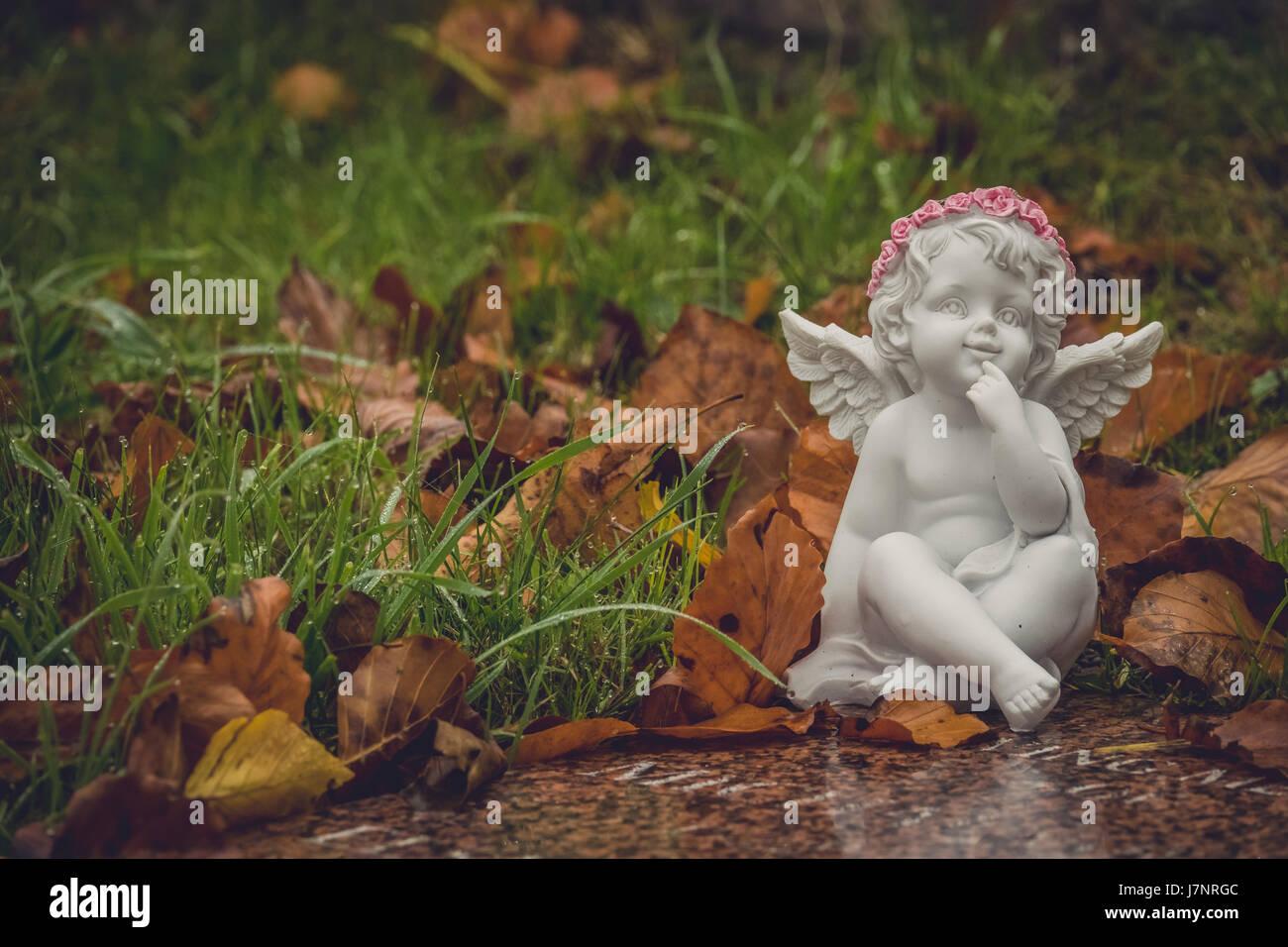 Tiny angel figure next to a child grave in cemetery Stock Photo - Alamy