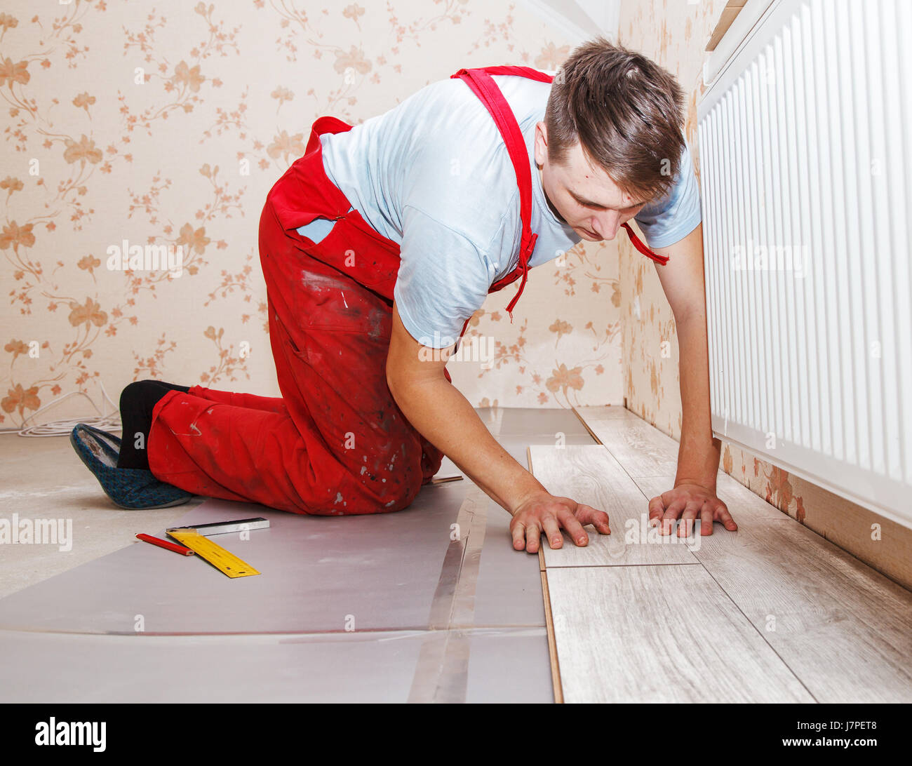 young handyman installing wooden floor in new house Stock Photo Alamy