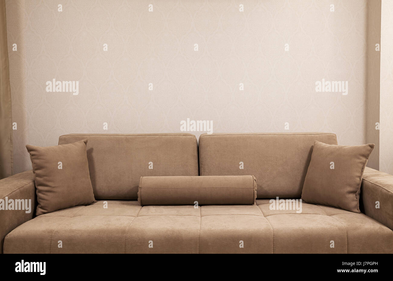 Modern and new couch in front of wall with decorative wallpapers. Stock Photo