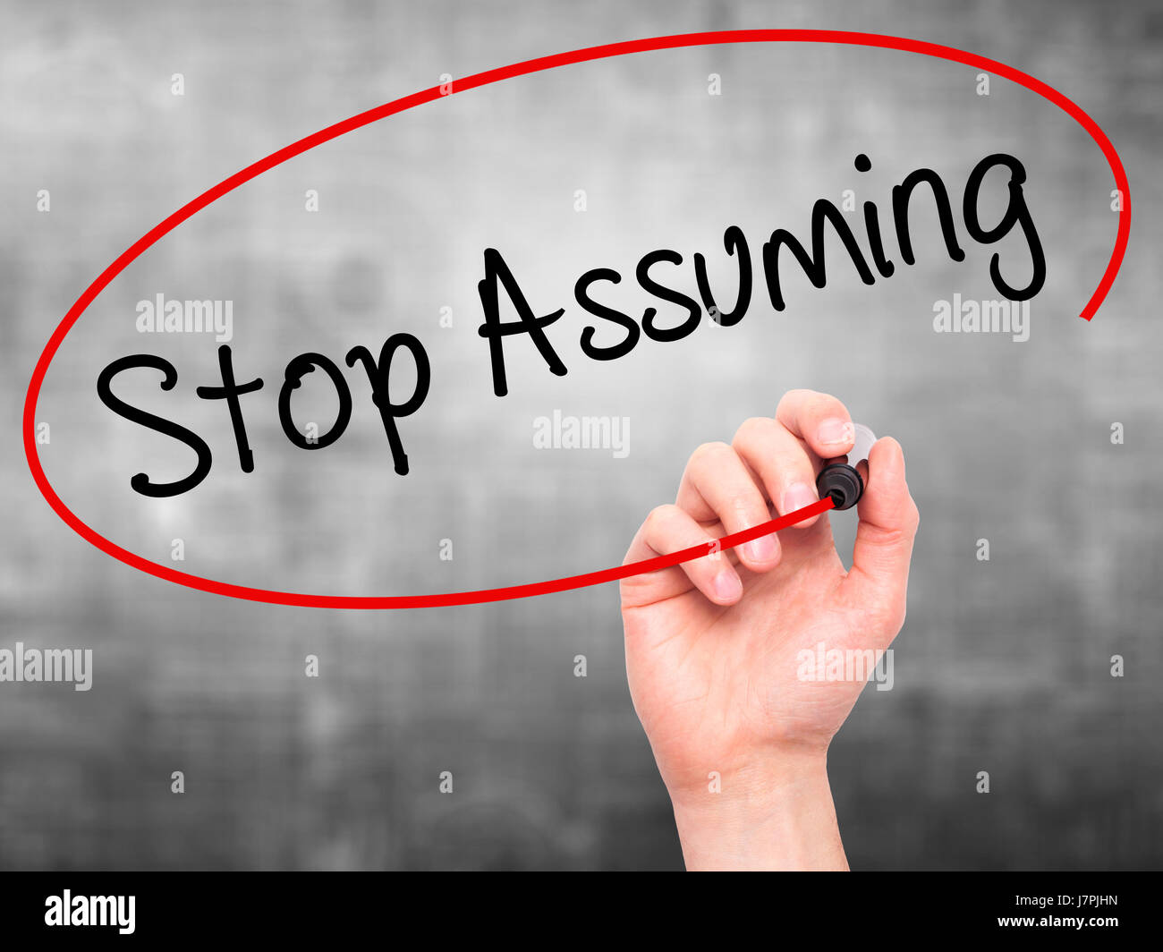 Man Hand writing Stop Assuming with black marker on visual screen. Isolated on background. Business, technology, internet concept. Stock Photo Stock Photo