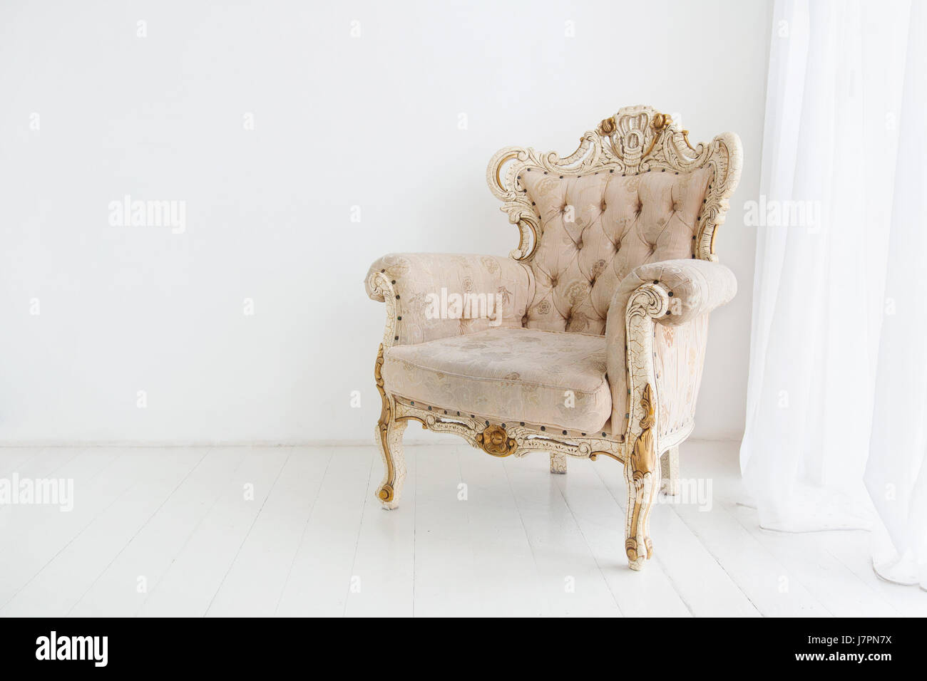 Vintage armchair against white wall in white room Stock Photo - Alamy