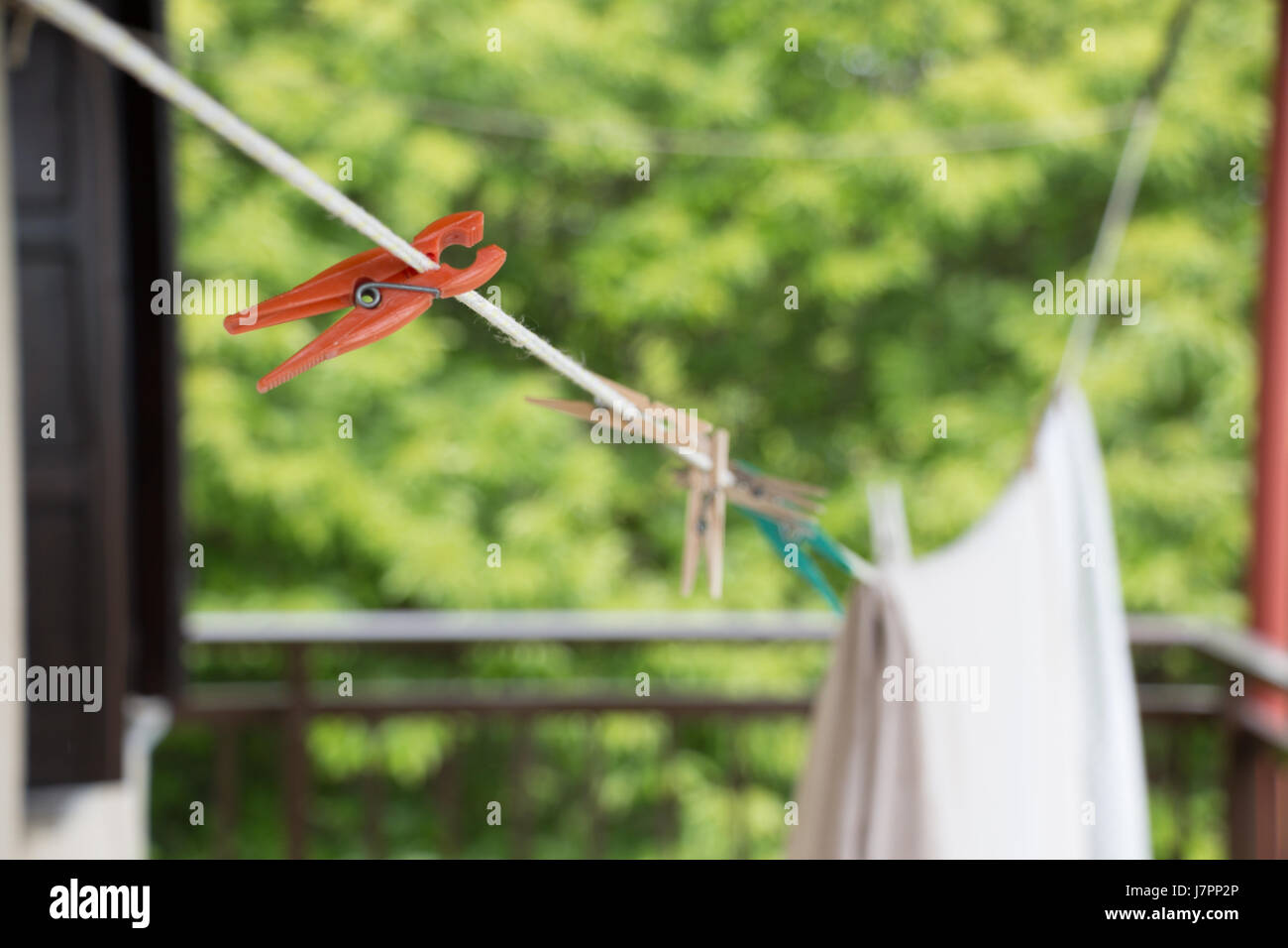 Closeup of a plastic peg on a washing line with clothespins and clothes blurred background. Stock Photo