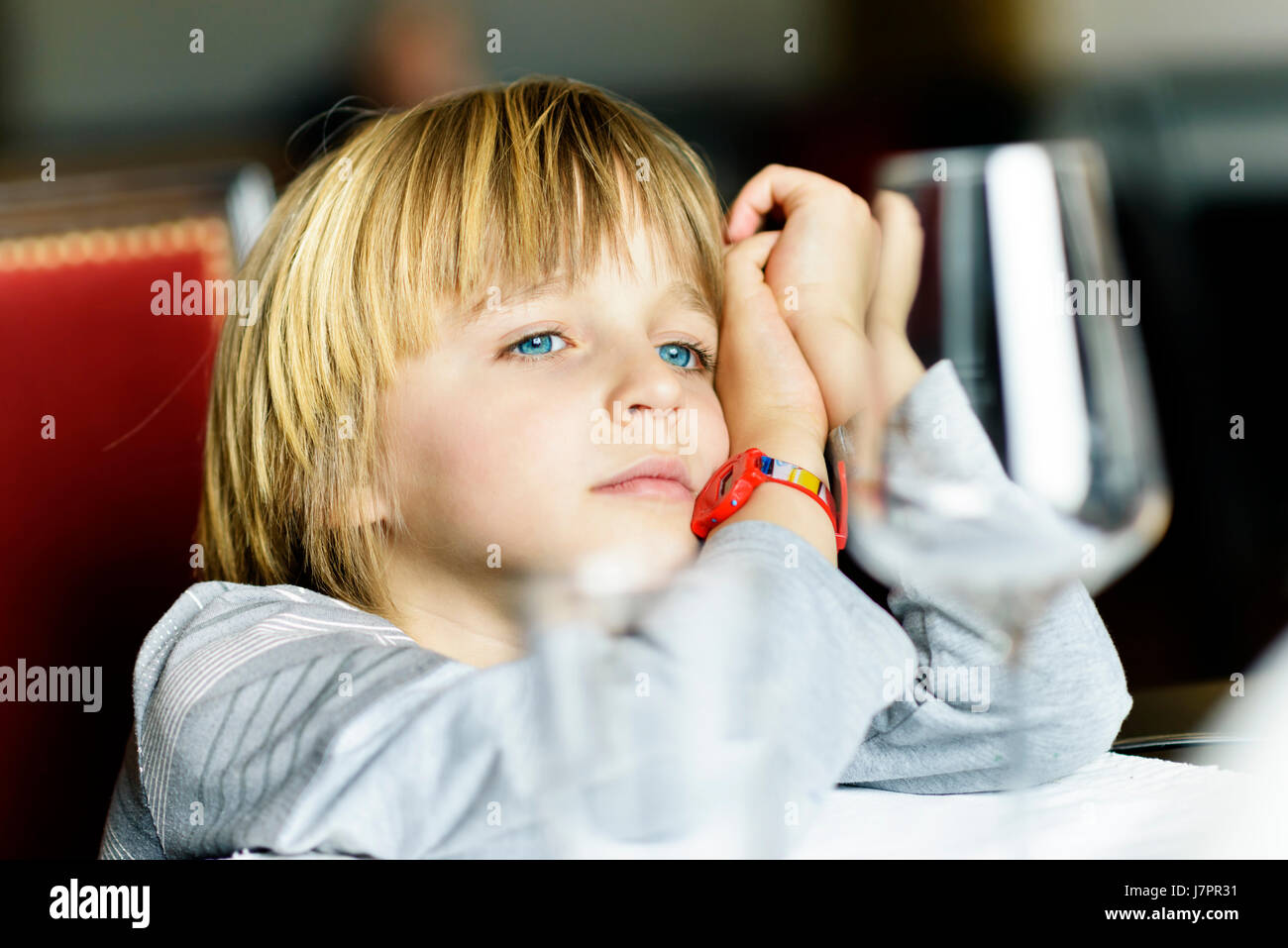 A serious child sitting alone at table in a restaurant Stock Photo