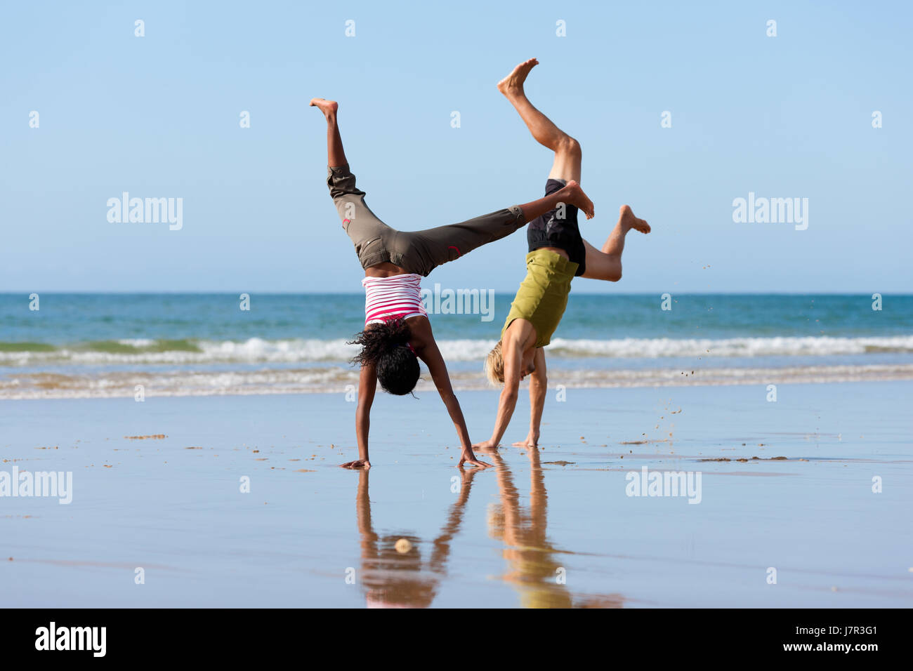 sporty couple doing gymnastics on the beach Stock Photo