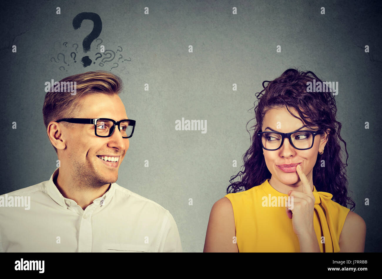 Does she like me? handsome man with question mark looking at an attractive girl flirting with him. Human emotions face expression perception Stock Photo