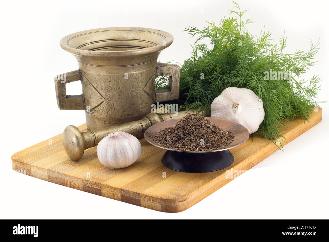 Still Life Spices, cumin ,marigold staminas in a copper vase on a wooden board on a background of a stern stupa for grinding spices, bunches of dill a Stock Photo